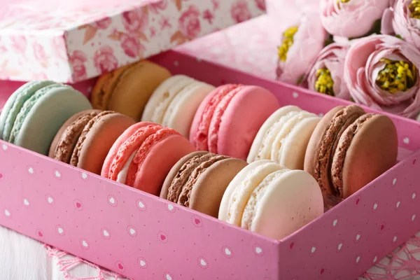 French macaroons in a pink box and flowers close-up. horizontal — Stock Photo, Image