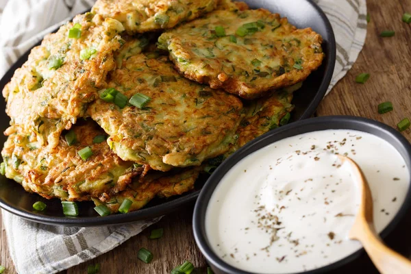 Cibo estivo: frittelle di zucchine con crema aspra primo piano. orizzonte — Foto Stock