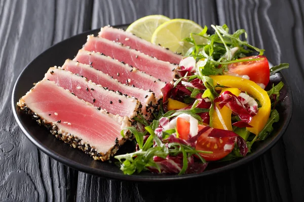 Belle nourriture : thon steak au sésame, citron vert et salade fraîche à proximité — Photo