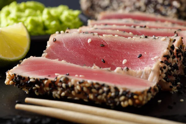 Beautiful sliced tuna steak in sesame and wasabi, lime macro. ho — Stock Photo, Image