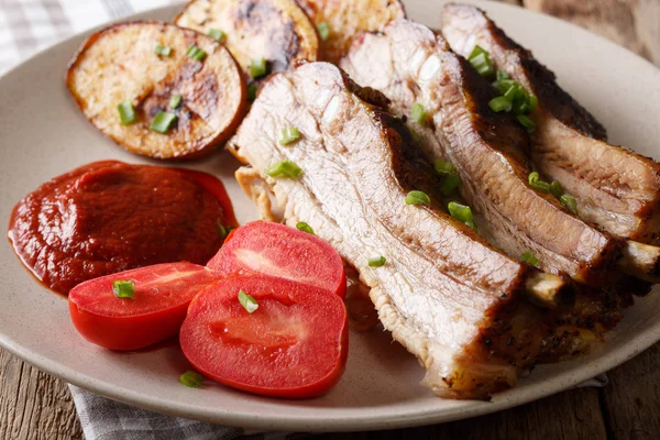 Fried hot vepřová žebra s omáčkou a pečenými brambory zblízka. Hori — Stock fotografie