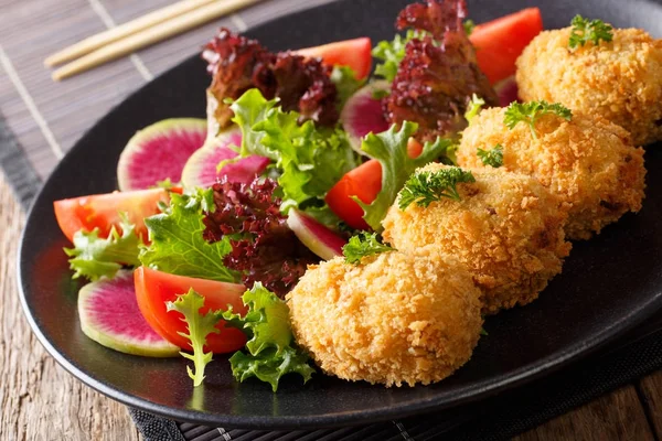 Японская кухня: картофельные крокеты и овощной салат крупным планом. ч — стоковое фото