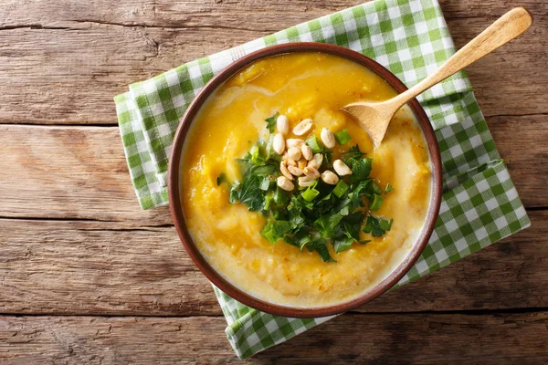 Spicy Thai pumpkin soup with peanuts and cilantro close-up in a — Stock Photo, Image