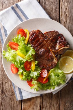 Taze sebze ve limon yakın çekim baharatlı T-Bone biftek. Vert