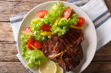 Taze sebze ve limon yakın çekim baharatlı T-Bone biftek. Hori