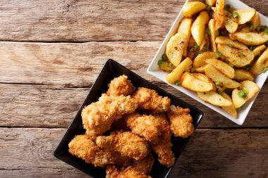 Ekmek kırıntısı kızarmış tavuk kanatları ve patates dilimleri yakın çekim. 