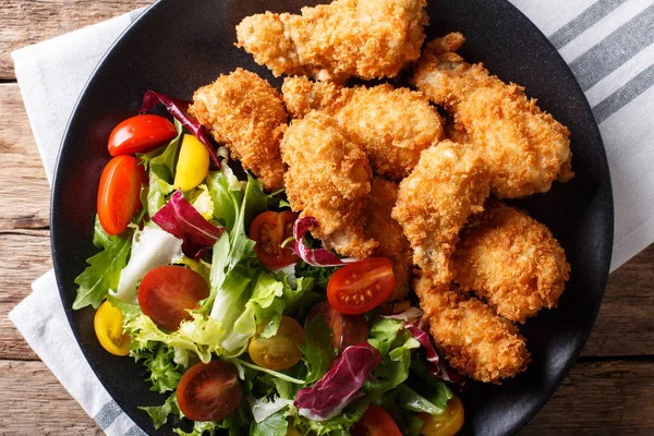 Хрустящие куриные крылышки в хлебных крошках и свежий салат крупным планом — стоковое фото