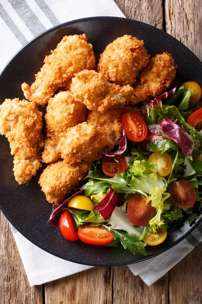 Crispy chicken wings in breadcrumbs and fresh salad close-up on