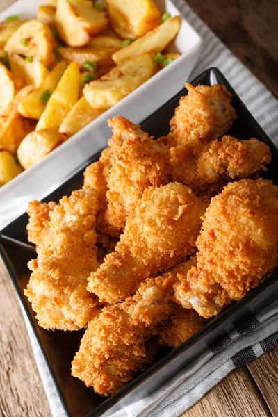 Kavrulmuş Tavuk kanatları ve patates dilimleri kapatın. dikey