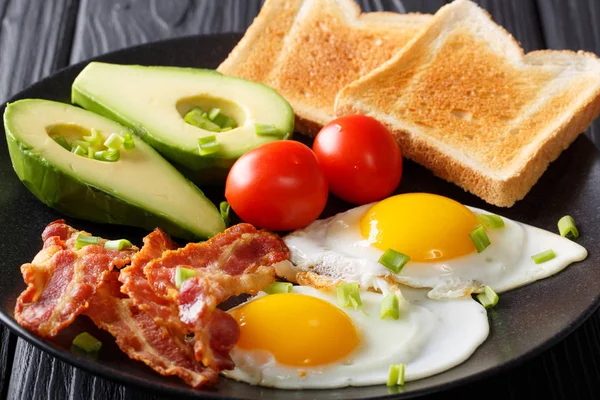 Stevig ontbijt: gebakken eieren met bacon, avocado, toast en toma — Stockfoto