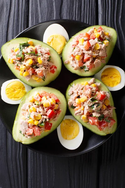 Ripe avocado with a salad of tuna and vegetables close-up. Verti — Stock Photo, Image