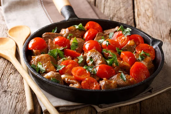 Guisado de carne de vaca delicioso com tomates e verdes close-up em uma frigideira — Fotografia de Stock