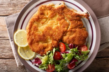 Veal milanese (cotoletta alla milanese) with lemon and fresh veg clipart