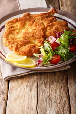 Fried veal cutlet Milanese with lemon and fresh salad of tomatoe clipart
