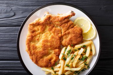 Fried veal cutlet Milanese with lemon and French fries close-up. clipart