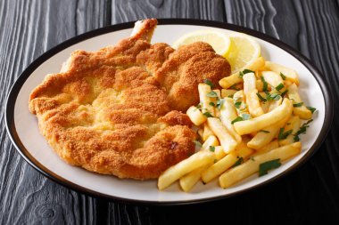 Fried veal cutlet Milanese with lemon and French fries close-up  clipart