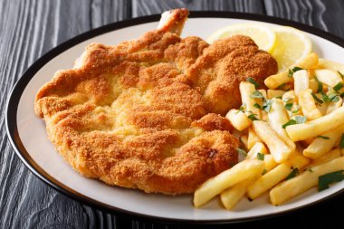 Veal alla Milanese in breadcrumbs with lemon and French fries cl clipart