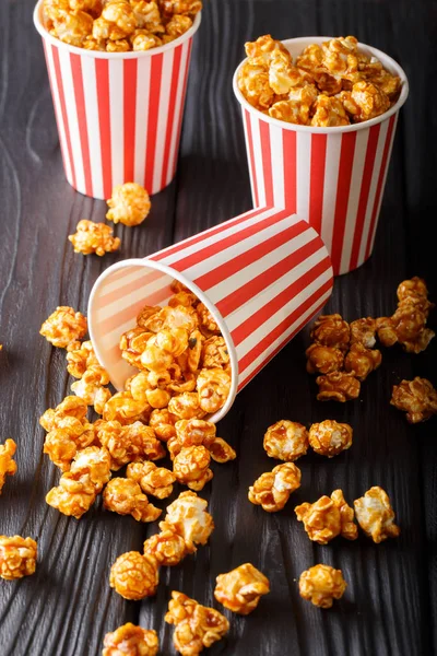 three striped boxes of sweet caramel popcorn close-up on wooden.