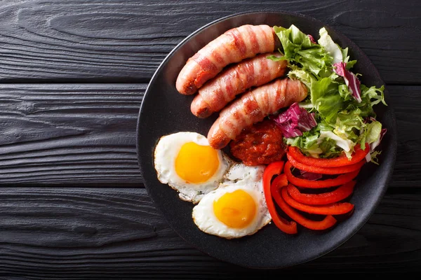 Домашняя жареная колбаса, завернутая в бекон, яйца, соус и свежий — стоковое фото