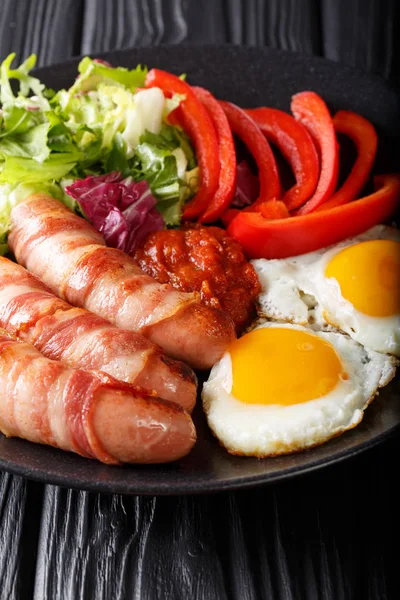 Вкусный завтрак из жареных колбас, завернутых в бекон, яйца и — стоковое фото