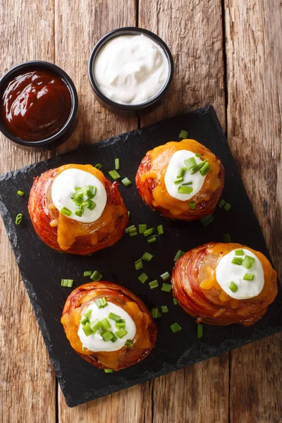 Batatas vulcânicas grelhadas embrulhadas em bacon coberto com queijo e — Fotografia de Stock