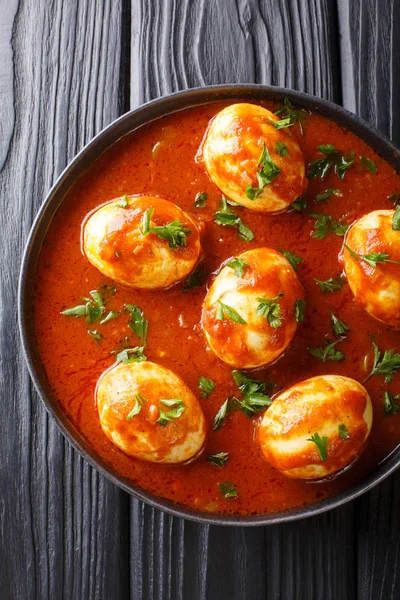 Boiled curry eggs in spicy sauce close-up in a plate. Vertical t — Stock Photo, Image