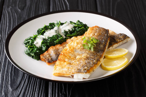 Healthy barbecue seabass fillet with braised spinach close-up on