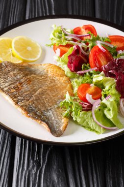 Fırında Dorado filetosu ve taze sebze salatası tabakta yakın plan.