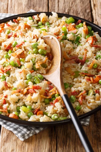 Gefrituurde rijst met groenten en spek close-up in een bord. Verticaal — Stockfoto