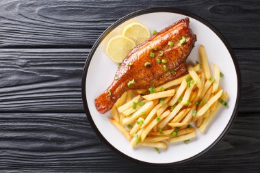 Whole cooked Sebastes fish with french fries and lemon on a plat clipart