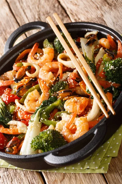 Seafood stir-fried with fresh vegetables close-up in a pan. vert — Stock Photo, Image