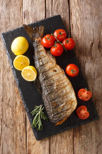 Salmone rosa intero alla griglia con pomodori e limone primo piano su un — Foto Stock