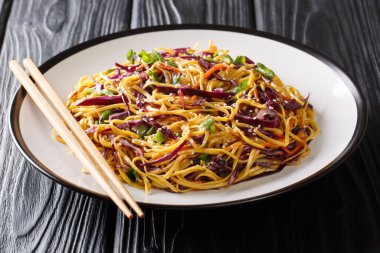 Serving egg noodles with red cabbage, carrots, green onions, gre