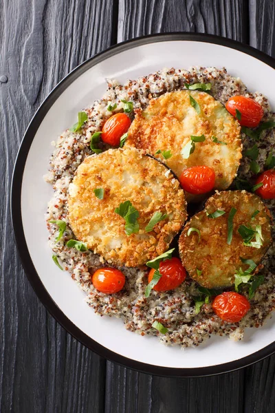 baked eggplant with tomatoes with a side dish of quinoa closeup on a plate on the table. Vertical top view from abov