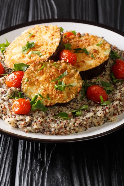 baked eggplant with tomatoes with a side dish of quinoa closeup on a plate on the table. vertica