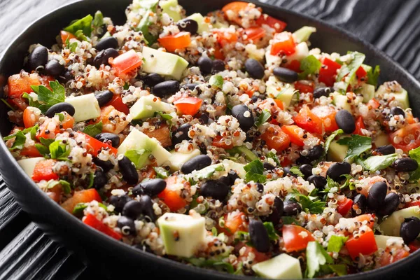 Mexican style quinoa with fresh avocado, peppers, tomatoes and black beans closeup in a plate on a table. horizonta