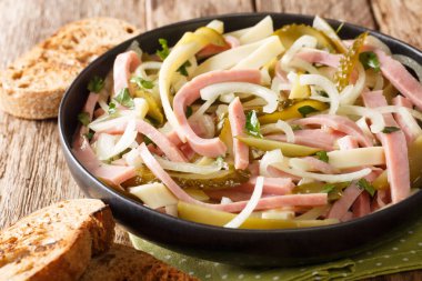 Sosis, peynir ve soğandan yapılmış İsviçre salatası. Baharatlı sos ile tatlandırılmış. Masanın üstünde. yatay
