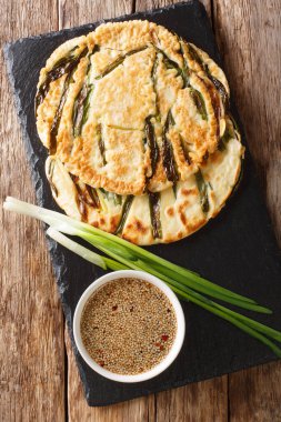 Masadaki tahtada yeşil soğanlı Kore gözlemesi Pajeon. Yukarıdan dikey üst görünüm