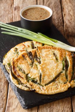 Masadaki tahtada yeşil soğanlı Pajeon Kore krepleri için temel tarif. dikey