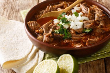 Mexican style slow cooked beef stew Birria de Res served with lime and tortilla closeup in a bowl on the table. horizonta clipart