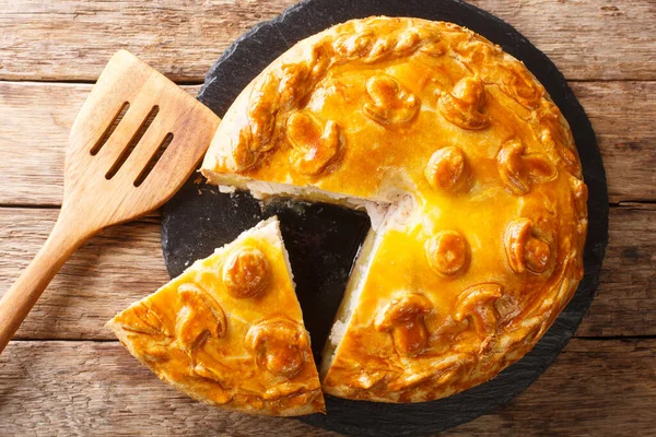 Traditional Russian sliced pie Kurnik close up on a slate board on the table. horizontal top view abov