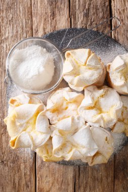 Hassas peynir kremalı İtalyan soffionisi keki ve masanın üzerindeki tahtaya yakın plan şeker tozu. Yukarıdan dikey üst görünüm