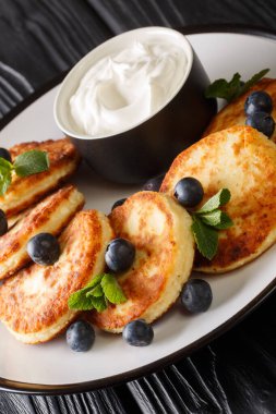 Yaban mersinli, naneli ve ekşi kremalı lezzetli şurup masanın üstünde. dikey