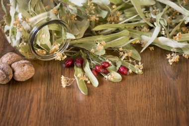 Kuru ıhlamur çiçek, kırmızı rose hips ve fındık sağlıklı kavramı görünümünü ahşap arka plan üzerinde.  