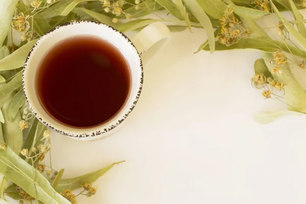 Frame of dry linden blossoms with cup of tea on white background. Top view. — Stock Photo, Image