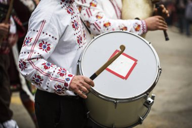 Bir davul üzerinde oynayan geleneksel folklor kostüm adam