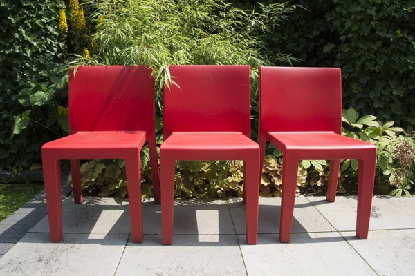 Três cadeiras vermelhas no jardim — Fotografia de Stock
