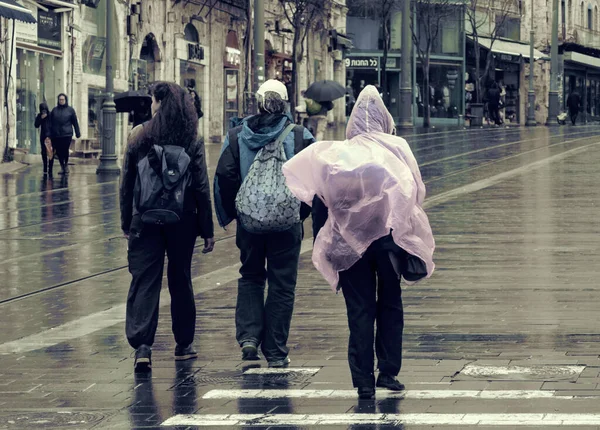 Tre donne che camminano sotto la pioggia con zaino e poncho — Foto Stock