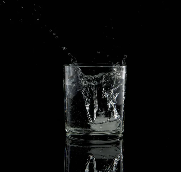 Splash from a falling ice cube in glass of water — Stock Photo, Image