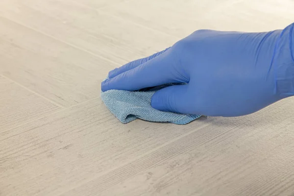 Mão com luva de borracha azul limpando um soalho — Fotografia de Stock